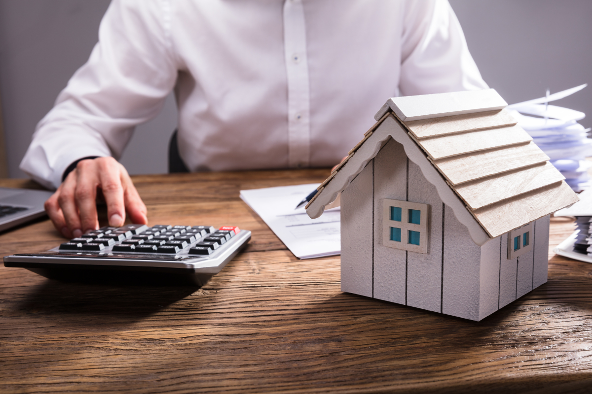 Déclaration impôt Pinel – Un homme effectue des calculs avec maison miniature sur le bureau