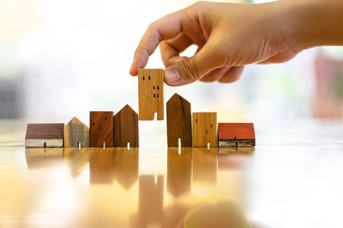 bordeaux débloque 35 millions pour le logement – Main choisissant une maison en bois parmi plusieurs modèles