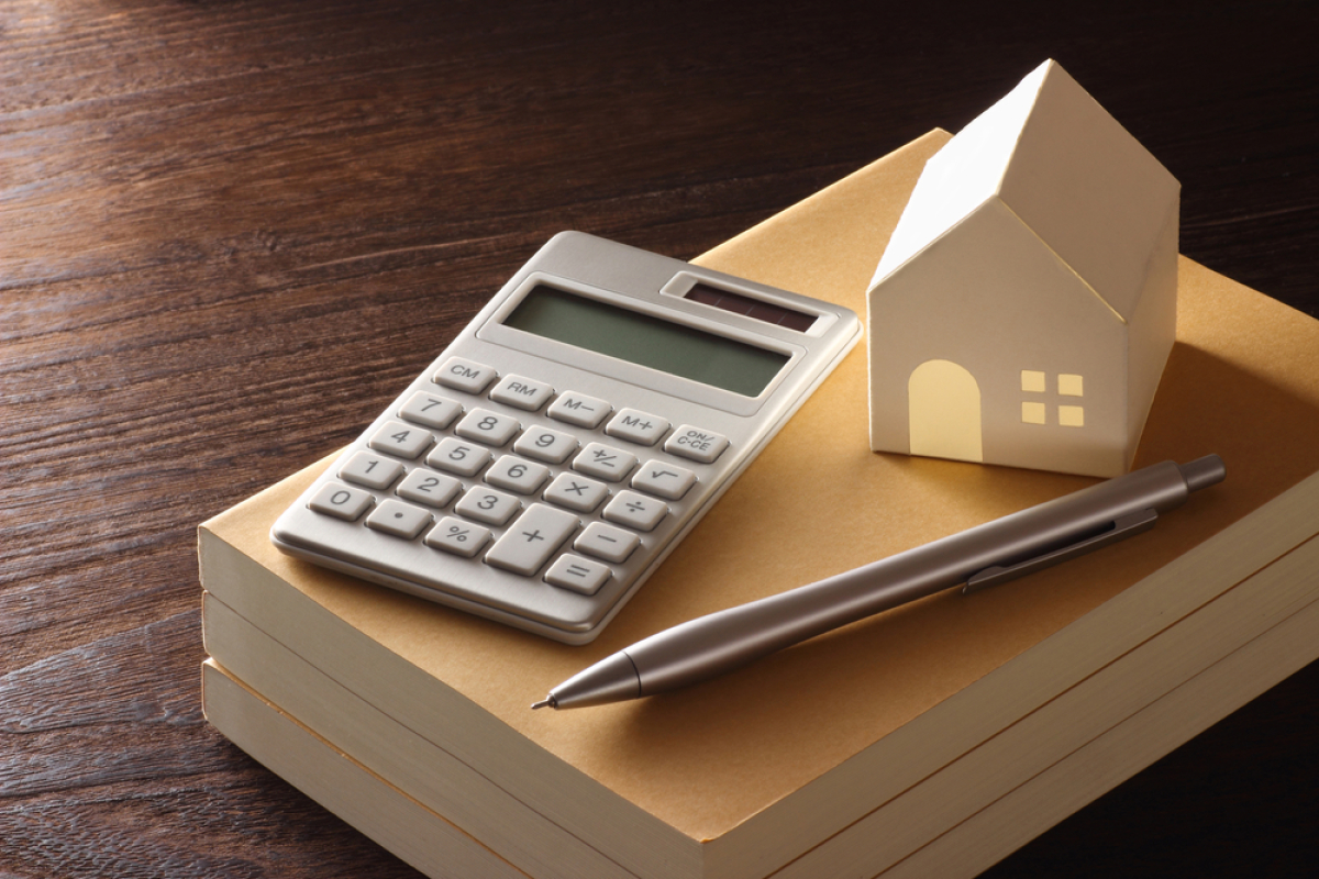 investissement locatif en couple – Une pile de livre avec une calculatrice, un stylo et une petite maison