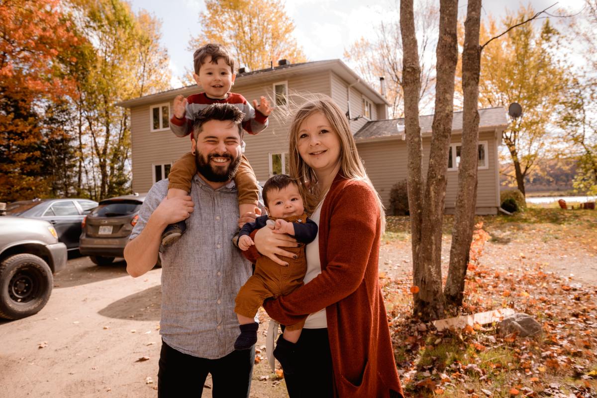 investissement locatif en couple – Une famille heureuse devant une maison en automne
