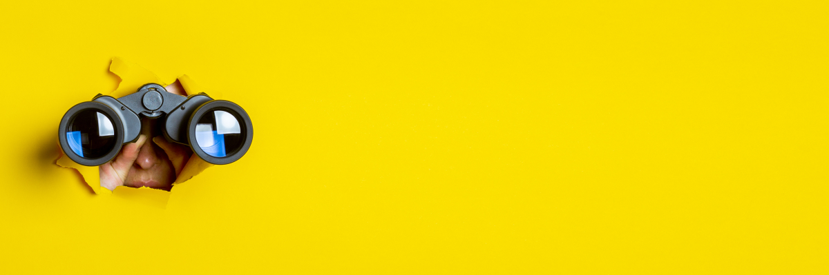 une personne perçant un décor jaune avec une paire de jumelles